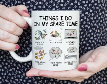 Könnte beinhalten: Eine weiße Keramiktasse mit einem humorvollen Design, das eine Liste von Dingen zeigt, die der Besitzer in seiner Freizeit tut, alles im Zusammenhang mit Vögeln. Der Text lautet "Things I do in my spare time" und enthält Illustrationen von Vögeln und Sätzen wie "Look for birds", "Watch birds", "Research birds", "Talk about birds", "Think about birds" und "Dream about birds".