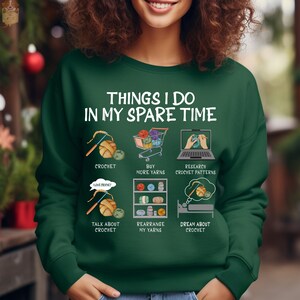 May include: Green sweatshirt with the text "Things I do in my spare time" and illustrations of crocheting, buying yarn, researching crochet patterns, talking about crochet, rearranging yarn, and dreaming about crochet.