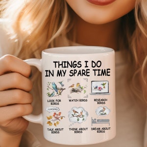 May include: White ceramic mug with a black outline and the text "THINGS I DO IN MY SPARE TIME" in black. The mug features illustrations of birds and the text "LOOK FOR BIRDS", "WATCH BIRDS", "RESEARCH BIRDS", "TALK ABOUT BIRDS", "THINK ABOUT BIRDS", and "DREAM ABOUT BIRDS".