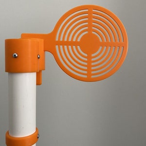 May include: Orange plastic target with a circular design, attached to a white PVC pipe with orange plastic clamps.