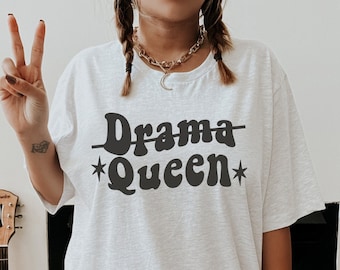 May include: A white t-shirt with the text "Drama Queen" in black with a star on either side of the word "Queen".
