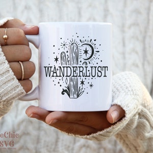 May include: White ceramic mug with a black and white illustration of a cactus, moon, stars, and the word "WANDERLUST".