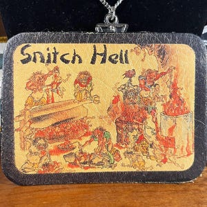 May include: A leather necklace with a silver pendant featuring a cartoon image of a scene with the text "Snitch Hell". The scene depicts a group of cartoon figures in a fiery setting.
