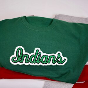 May include: A green sweatshirt with a white and green embroidered patch that says "Indians" on it.