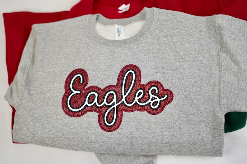 May include: Gray sweatshirt with a red glitter "Eagles" design.