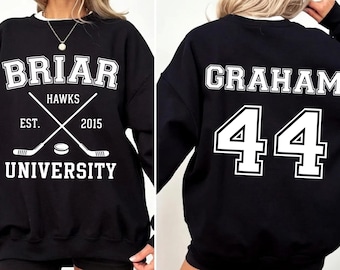 May include: A black crewneck sweatshirt featuring white screen-printed graphics. The front displays 'BRIAR UNIVERSITY', 'HAWKS', 'EST. 2015', and crossed hockey sticks with a puck. The back features the name 'GRAHAM' above the large jersey number '44'.