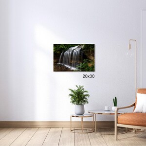 May include: A photograph of a waterfall cascading down a rocky cliff face, surrounded by lush green foliage. The water is clear and sparkling, and the sunlight is filtering through the trees.