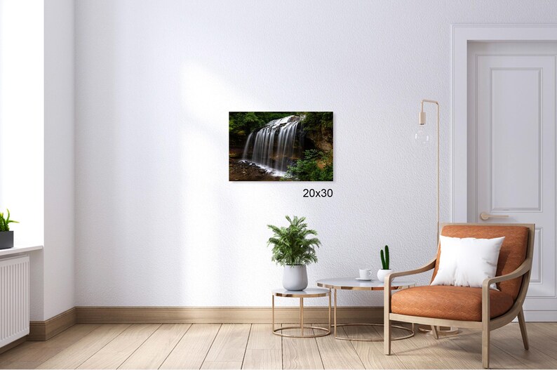 May include: A photograph of a waterfall cascading down a rocky cliff face, surrounded by lush green foliage. The water is clear and sparkling, and the sunlight is filtering through the trees.