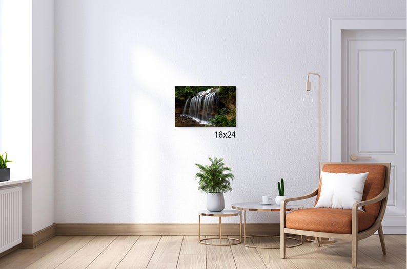 May include: A photograph of a waterfall cascading over rocks in a lush green forest. The water is clear and flowing over the rocks, creating a beautiful natural scene. The image is taken from a low angle, giving the viewer a sense of the height of the waterfall.