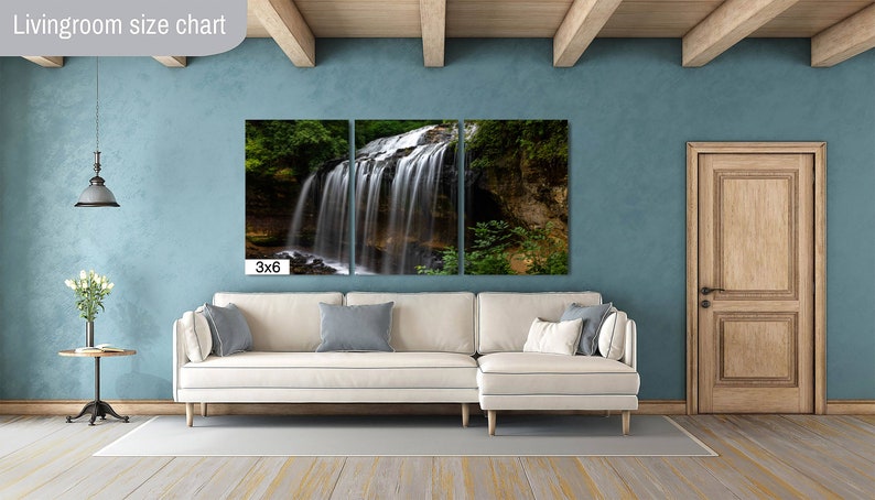 May include: A three-panel canvas print of a waterfall in a forest. The print is hanging on a wall in a living room with a white couch and a wooden door. The text "3x6" is printed below the canvas.