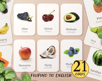 May include: 21 flashcards featuring pictures of fruits and vegetables, with their names in both Filipino and English. The cards are white with black text and are arranged in a grid on a wooden surface.