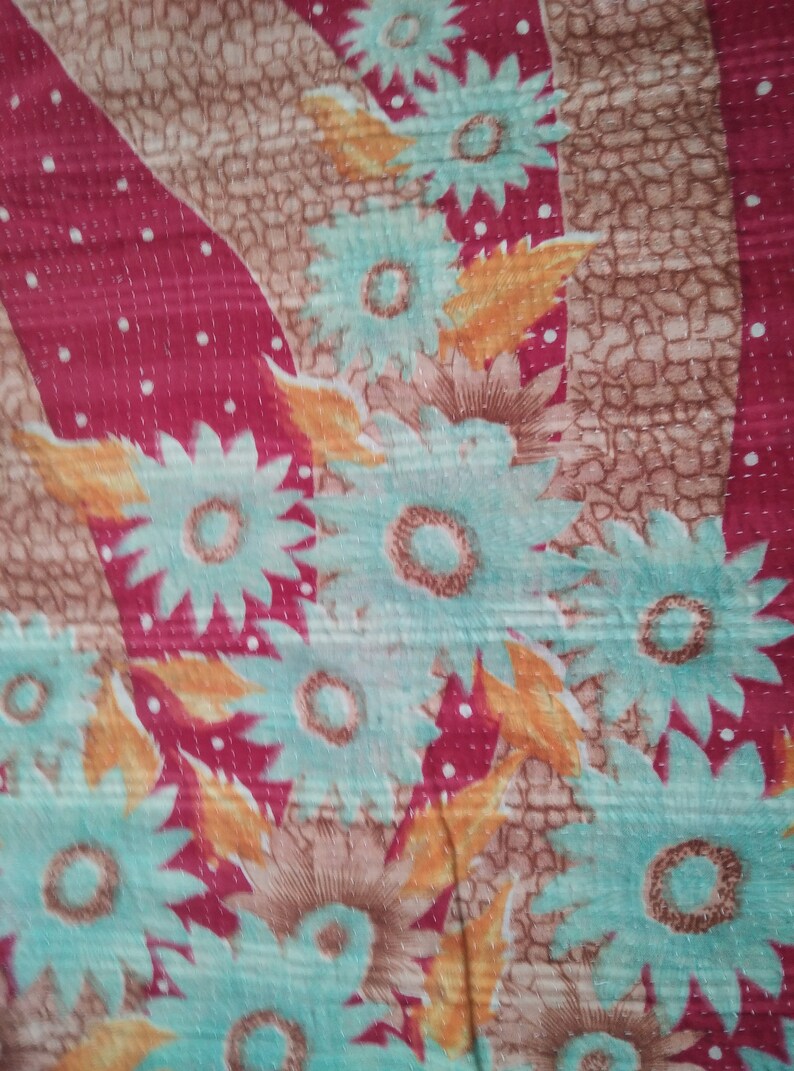 May include: A close-up of a fabric with a floral pattern. The fabric is red with white dots and features a repeating pattern of blue and yellow flowers.