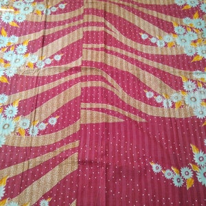 May include: A red fabric with a white polka dot pattern and a brown and white striped pattern. The fabric has a floral design with yellow and blue flowers.