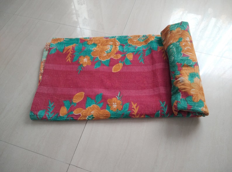 May include: A pink and green floral kantha quilt with a striped pattern. The quilt is rolled up and ready to be used.
