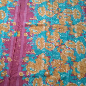 May include: A pink and teal floral patterned fabric with a quilted texture. The fabric features a repeating pattern of large, yellow flowers with teal leaves.