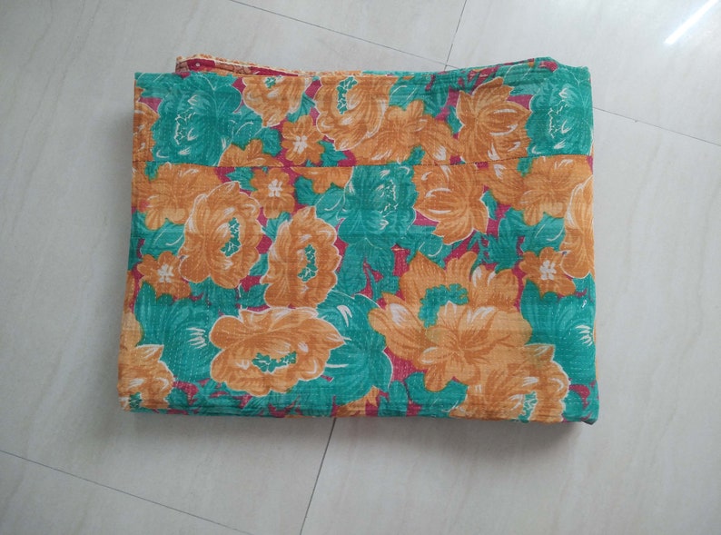 May include: A folded floral patterned blanket in shades of green, orange, and red.