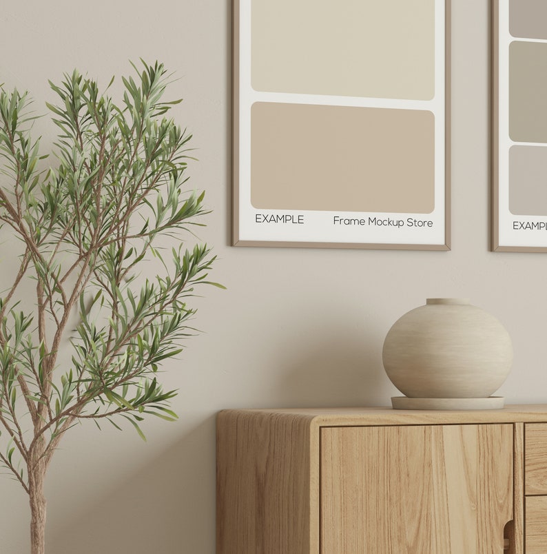 May include: A wooden cabinet with a rounded edge and a light-colored, spherical vase on top. Two framed art prints with neutral color swatches hang on the wall. The text "EXAMPLE Frame Mockup Store" is visible on the prints.