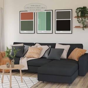 May include: A black sectional sofa with a variety of throw pillows in a living room setting. The sofa is in front of a white wall with three framed abstract art prints. The prints are in black, green, and brown colours. The text on the prints reads "With natural reflections to add realism to your photos."  "EXAMPLE Frame Mockup Store"