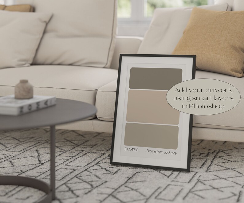 May include: A black picture frame mockup with a white mat and a light brown background. The frame is sitting on a white couch with a brown throw pillow. The text "Add your artwork using smart layers in Photoshop" is written on the image. The text "EXAMPLE Frame Mockup Store" is at the bottom of the frame.