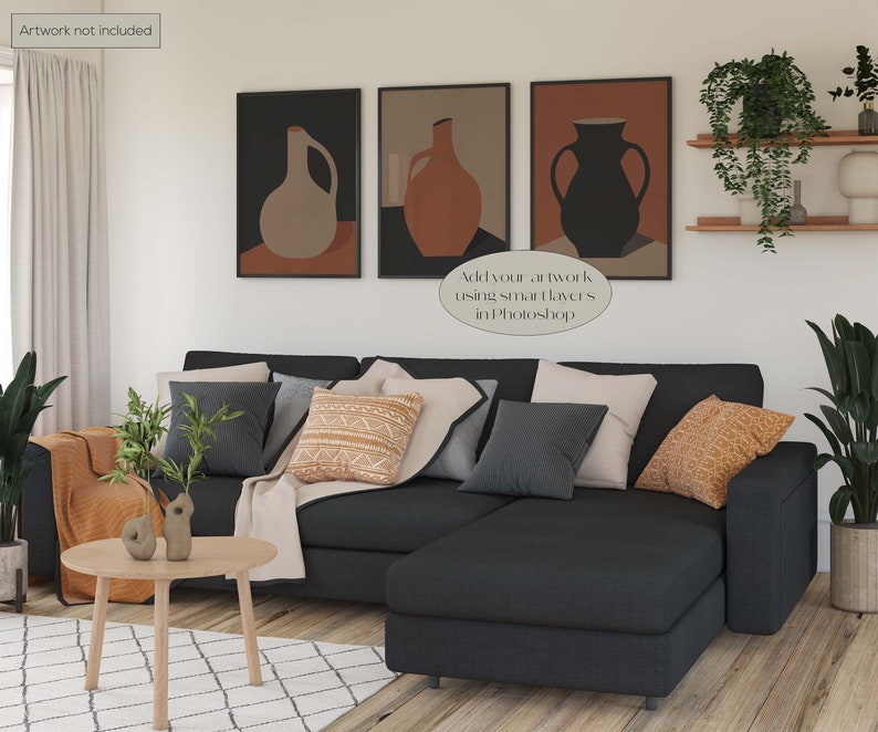 May include: A sectional sofa with a chaise lounge in a dark grey fabric. The sofa is decorated with throw pillows in various colours and patterns, including a brown and white patterned pillow, a grey pillow, and a beige pillow. There are two small decorative objects on a wooden coffee table in front of the sofa. The wall behind the sofa is decorated with three framed abstract art prints featuring vases in shades of brown, beige, and black. The text "Add your artwork using smart layers in Photoshop" is visible in the image.