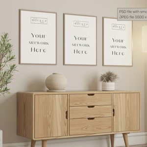 May include: Three framed art prints with the text "Your Artwork Here" hang above a wooden cabinet. A decorative vase and potted plant sit on the cabinet. A floor lamp and a potted plant are also in the scene.
