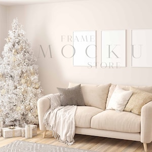 May include: A white couch with three pillows and a throw blanket in a living room setting with a white Christmas tree and three white picture frames on the wall. The frames are empty and ready for your design.