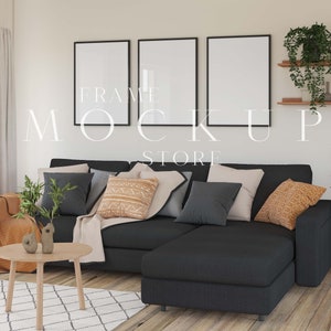 May include: A black sectional sofa with a light beige throw blanket and cushions in various shades of grey, brown, and orange. The sofa is in a living room setting with a wooden coffee table and a plant in a pot. Three black framed pictures are hanging on the wall behind the sofa.