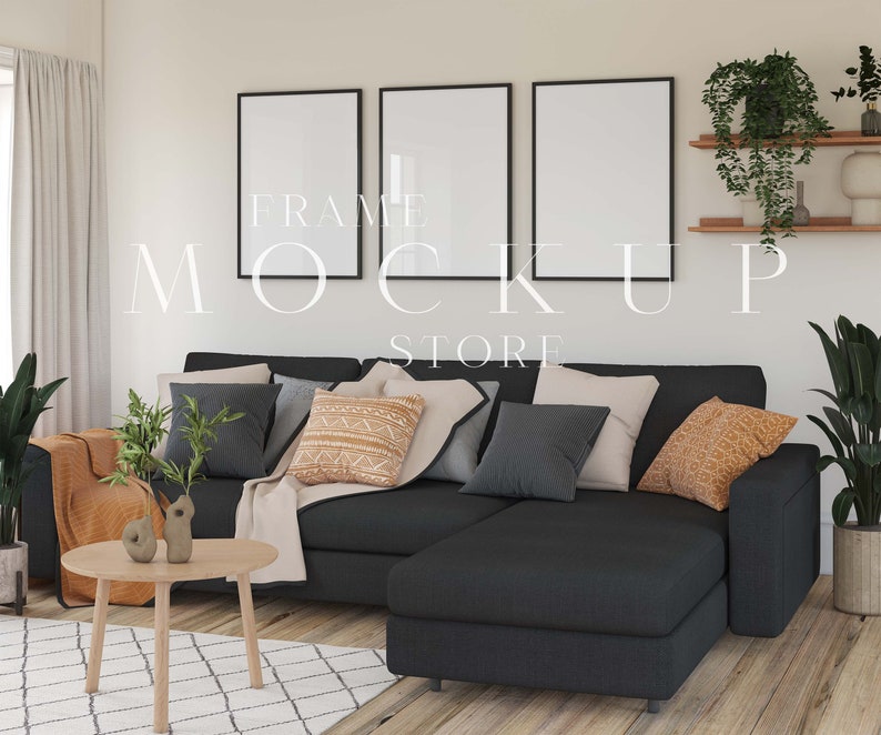 May include: A black sectional sofa with a light beige throw blanket and cushions in various shades of grey, brown, and orange. The sofa is in a living room setting with a wooden coffee table and a plant in a pot. Three black framed pictures are hanging on the wall behind the sofa.