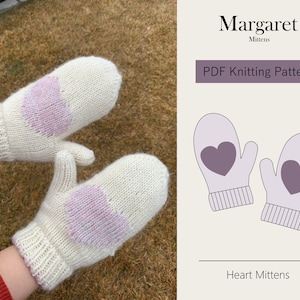Puede incluir: Un par de mitones de punto blanco con diseños de corazones rosas. Los mitones se muestran siendo usados por una persona. La imagen también incluye una superposición de texto que dice "Margaret Mittens PDF Knitting Pattern Heart Mittens".