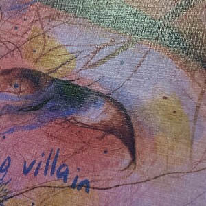 May include: A close-up of a textured canvas with a watercolor painting of a bird's wing and the words "my villain" written in blue ink.
