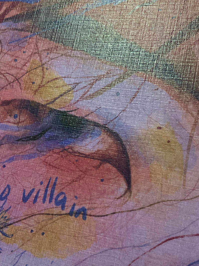 May include: A close-up of a textured canvas with a watercolor painting of a bird's wing and the words "my villain" written in blue ink.
