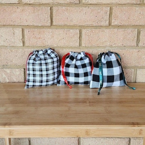 May include: Three black and white gingham drawstring bags with red, green, and white ribbon ties.