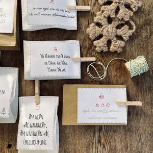K&ouml;nnte beinhalten: Ein Satz wei&szlig;er Papiert&uuml;ten mit aufgedruckten Zahlen und Text. Die T&uuml;ten sind mit W&auml;scheklammern an einer Holzoberfl&auml;che befestigt. Der Text auf den T&uuml;ten enth&auml;lt die Zahlen 2, 4, 5 und 6 sowie S&auml;tze wie "is mir egal wie alt ich bin, ich will meinen Adventskalender!" und "egal, du wei&szlig;t schon... sch&ouml;nen nikolaus".