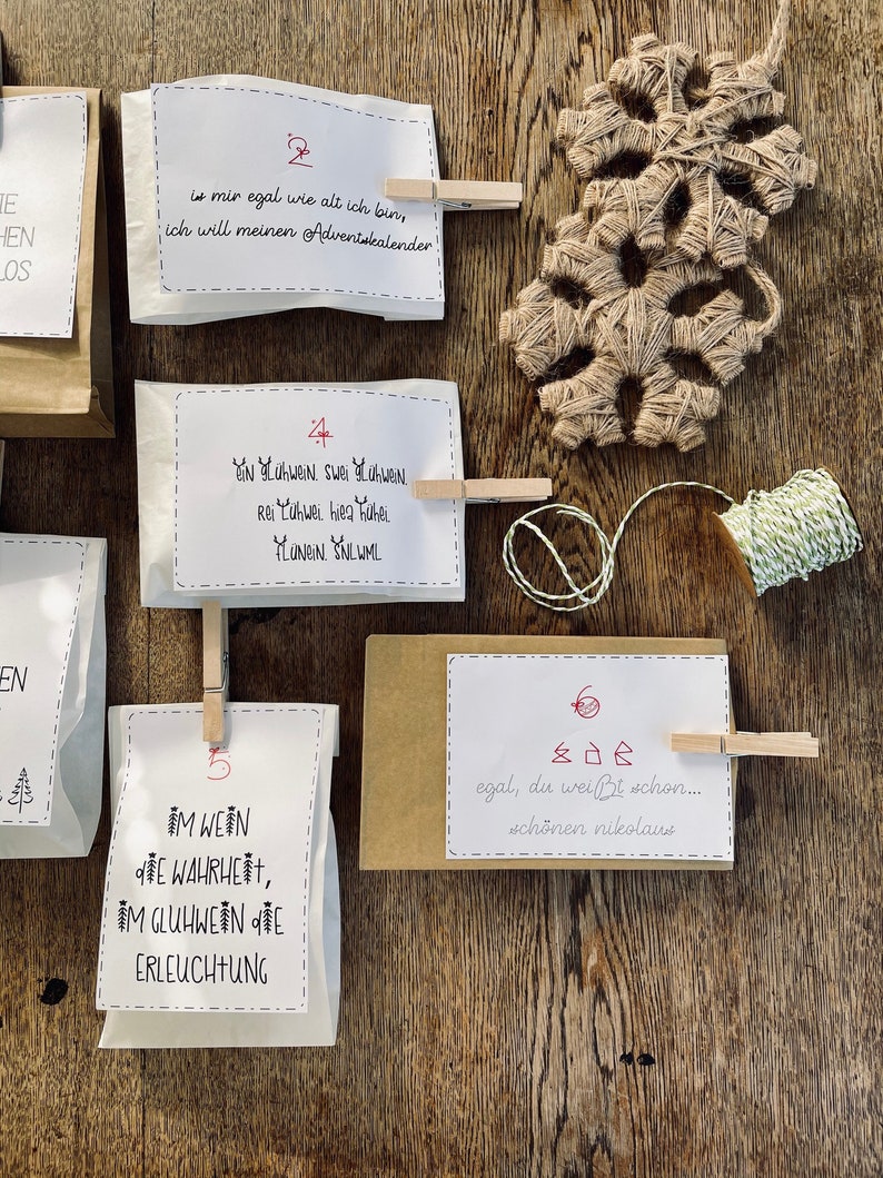K&ouml;nnte beinhalten: Ein Satz wei&szlig;er Papiert&uuml;ten mit aufgedruckten Zahlen und Text. Die T&uuml;ten sind mit W&auml;scheklammern an einer Holzoberfl&auml;che befestigt. Der Text auf den T&uuml;ten enth&auml;lt die Zahlen 2, 4, 5 und 6 sowie S&auml;tze wie "is mir egal wie alt ich bin, ich will meinen Adventskalender!" und "egal, du wei&szlig;t schon... sch&ouml;nen nikolaus".