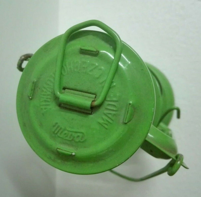 以下が含まれることがあります： 緑色の金属製の灯油ランプ。上部にハンドルがあり、側面に「OMEGA MADE IN INDIA」の文字が書かれています。