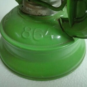 以下が含まれることがあります： 丸いベースと側面に「864」と印刷された緑色の金属製ケロシンランプです。