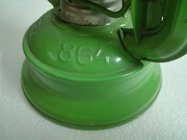 以下が含まれることがあります： 丸いベースと側面に「864」と印刷された緑色の金属製ケロシンランプです。