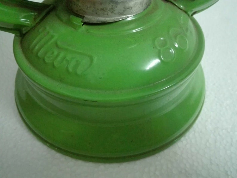 以下が含まれることがあります： 銀色のトップと側面に「Mera」という文字が刻印された緑色の金属製のケロシンランプです。