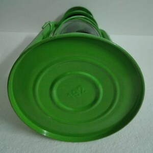 以下が含まれることがあります： ガラスのグローブと円形のベースが付いた緑色の金属製のランタン。ベースには小さなエンボス加工のデザインが施されています。