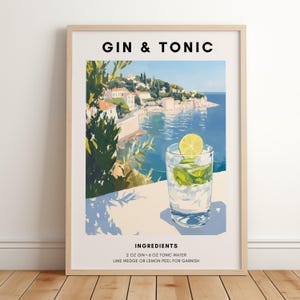 Könnte beinhalten: Gerahmter Kunstdruck mit einem "Gin & Tonic"-Cocktail. Das Bild zeigt ein Glas des Getränks mit Limette und eine Küstenlandschaft. Der Text "GIN & TONIC" steht oben, die Zutaten sind unten aufgeführt.
