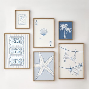 May include: A set of framed art prints with a beach theme. Includes a blue and white seashell playing card, a starfish, palm trees, a bikini, and "Beach Club" tickets. The frames have a gold finish.