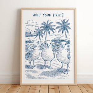May include: A framed art print featuring three cartoon seagulls on a beach, with palm trees and umbrellas in the background. The text "HIDE YOUR FRIES!" is at the top. The artwork is in shades of blue and white.