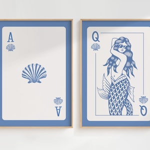 May include: Two framed art prints. The left print is the Ace of Seashells playing card, with a large seashell in the center and smaller ones at the top and bottom. The right print is the Queen of Seashells, a mermaid wearing sunglasses.