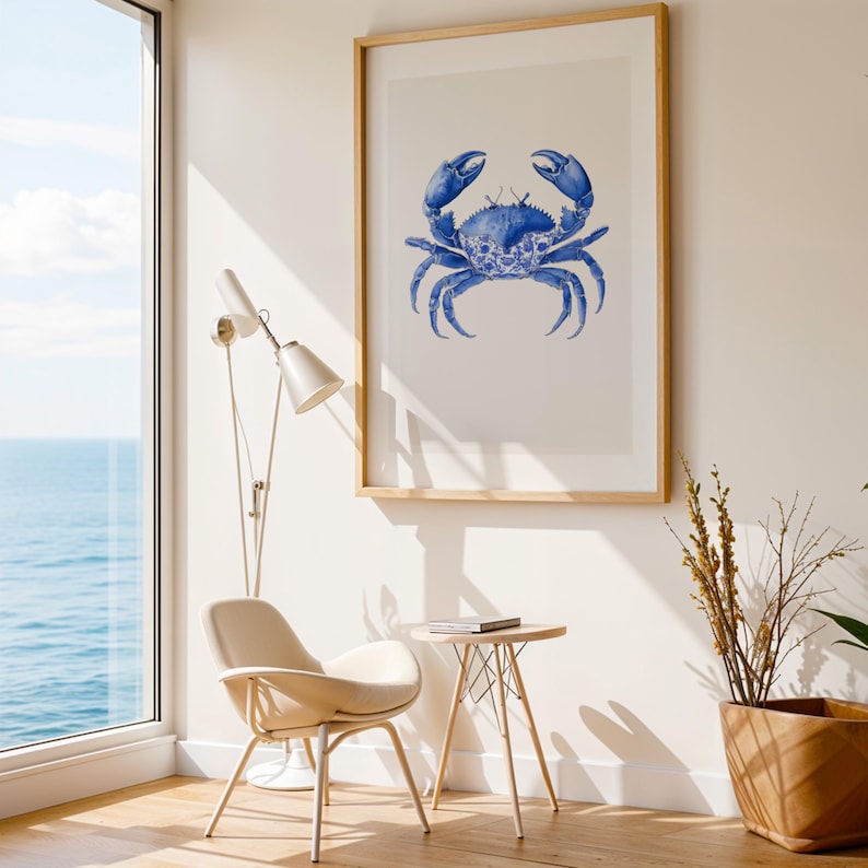 May include: A framed art print featuring a blue crab illustration. The crab is depicted in a detailed, watercolor style with intricate patterns. The artwork is set against a white background and framed in natural wood, suitable for coastal decor.