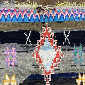May include: A colorful Moroccan rug with a diamond-shaped pattern in the center. The rug is made of wool and has a fringe border.