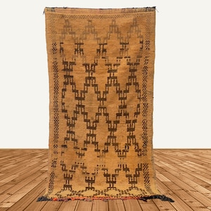 May include: A brown and black geometric patterned rug with a fringe border. The rug is woven with a traditional Moroccan design.