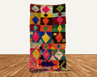 May include: A colorful Moroccan rug with a geometric pattern of squares and diamonds in shades of red, blue, green, yellow, orange, and pink.