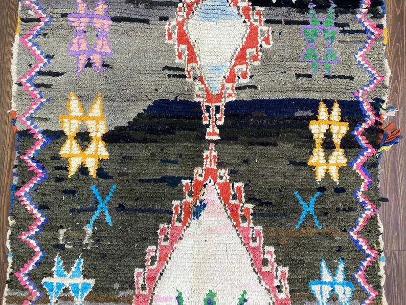 May include: A colorful Moroccan rug with a geometric pattern in shades of red, blue, yellow, green, and pink. The rug has a dark background and a white center.