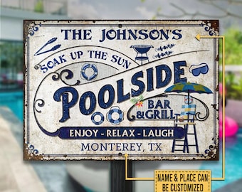 Może przedstawiać: Biały metalowy znak z niebieskim tekstem, na którym widnieje napis "The Johnson's Poolside Bar & Grill" z tekstem "Soak Up The Sun" nad nim. Znak zawiera również tekst "Enjoy - Relax - Laugh" i "Monterey, TX".