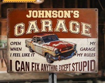 May include: A rusty red and white metal sign with the text "JOHNSON'S GARAGE" in large, bold letters. The sign also features a vintage car, the text "OPEN WHEN I FEEL LIKE IT", and the text "MY GARAGE MY RULES I CAN FIX ANYTHING EXCEPT STUPID".
